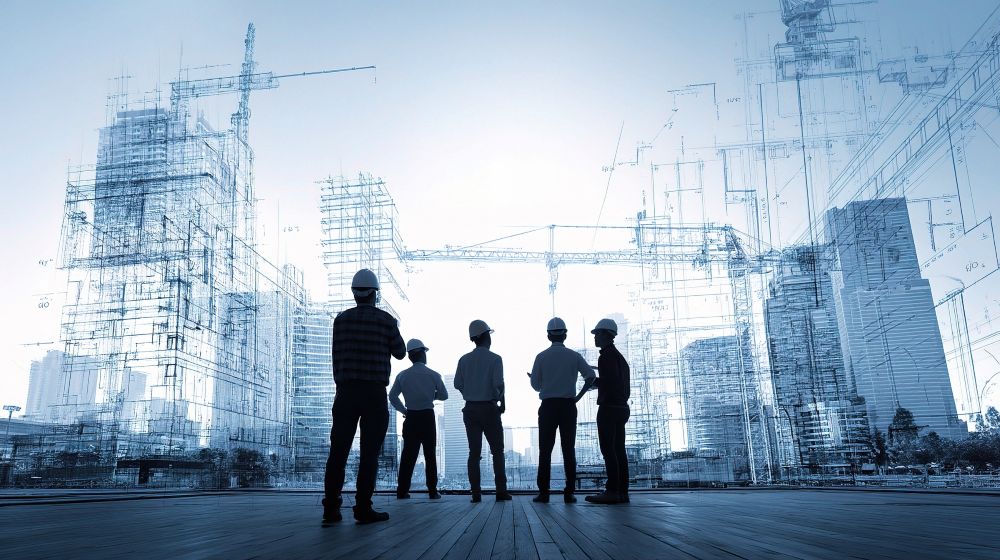 Silhouettes of construction workers standing in front of a city skyline